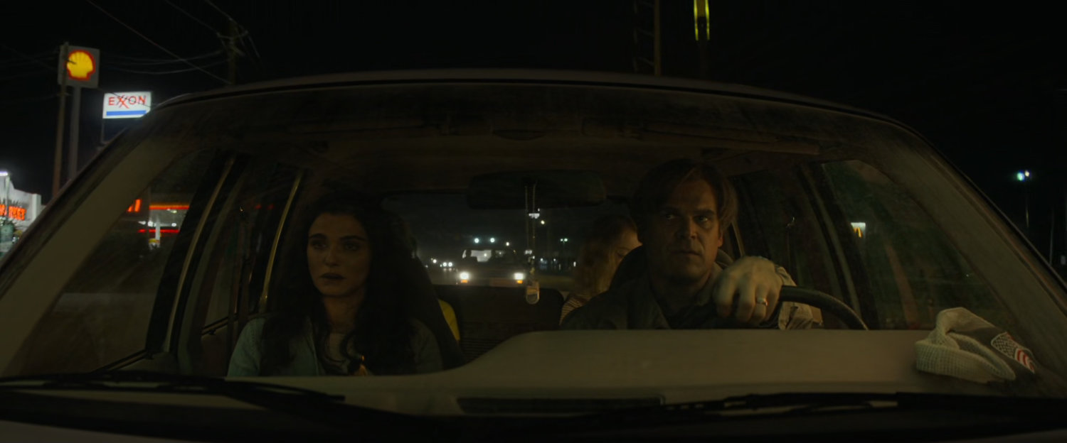 Alexei and Melina in family car with Shell and Exxon signs outside.