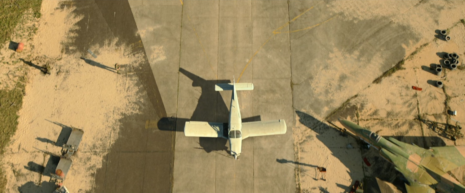 Aerial of white Cessna on dirty Cuban runway.