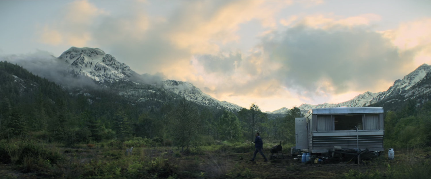 A mobile home in wooded clearing.