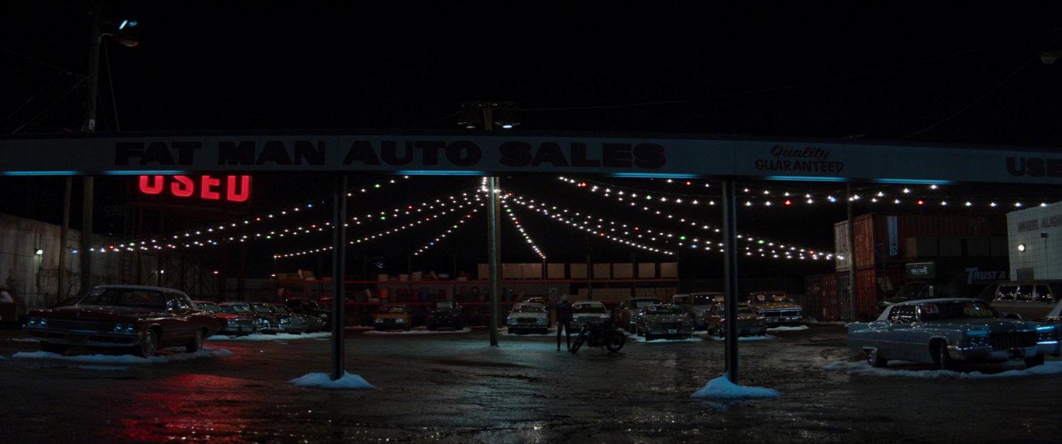 Exterior of Fat Man Used Cars at night.