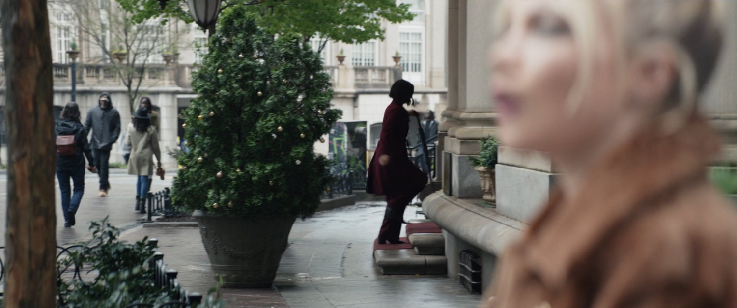 Yelena watching Eleanor walking on sidewalk outside of Kingpin's hotel.