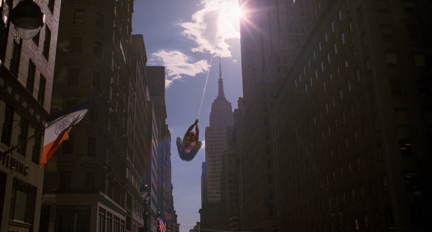 Spider-Man swinging down city street.