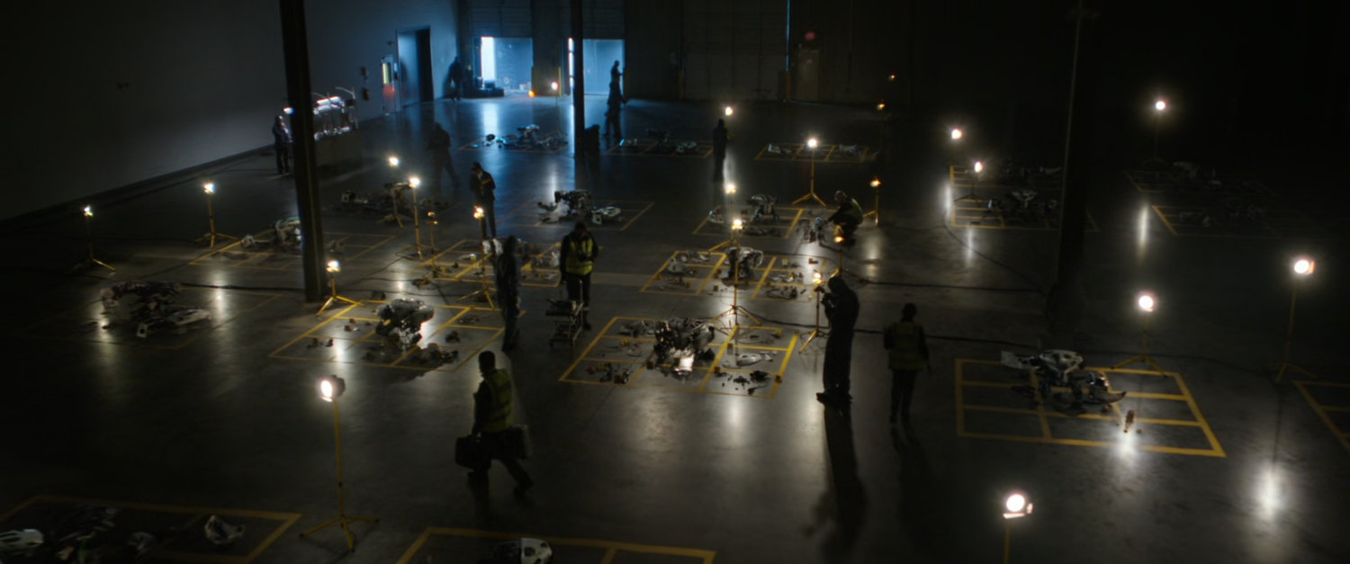 Interior of a Stark Industries warehouse with debris in numbered boxes on floor.