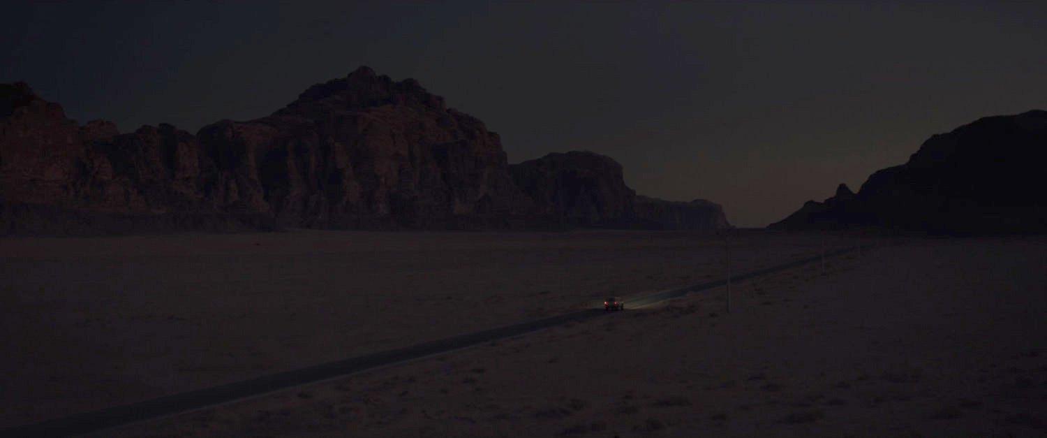 A lone car on a road in the Egyptian desert at twilight.