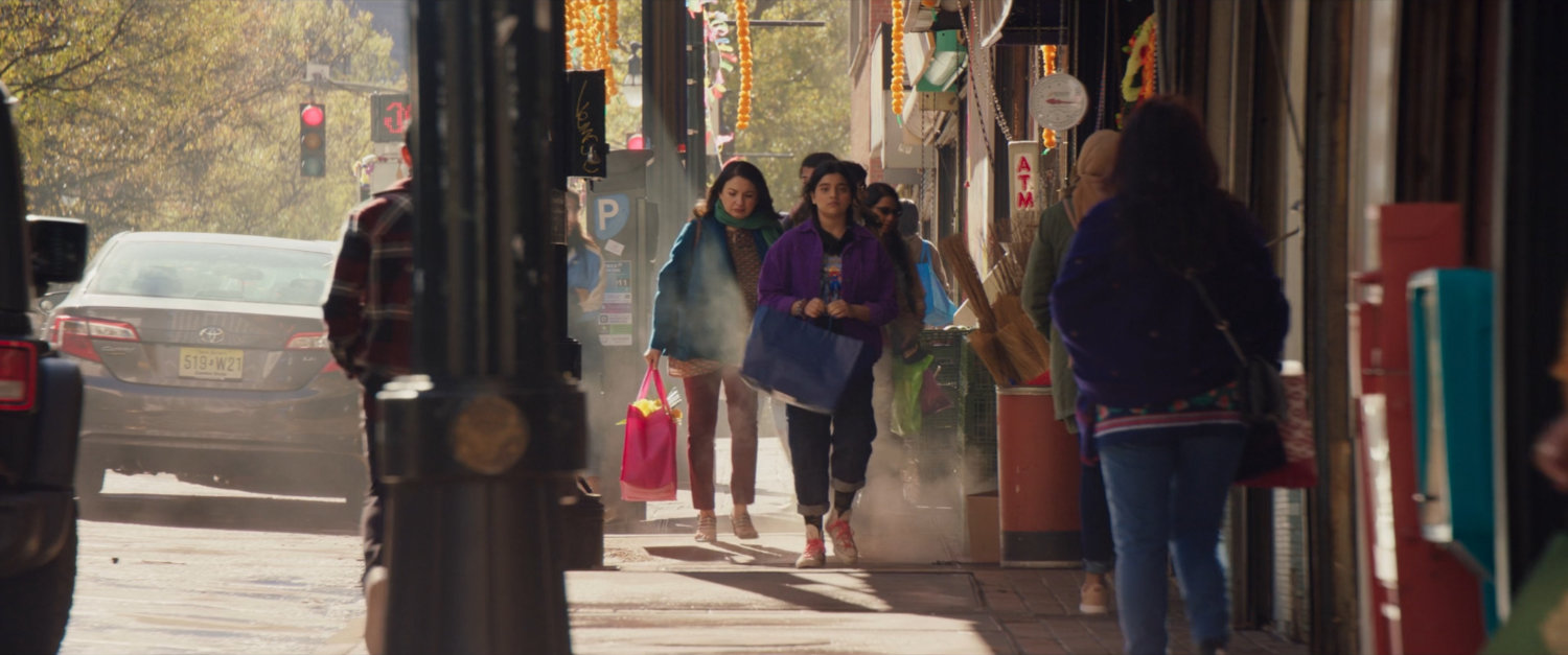 Kamala and Muneeba walk down sidewalk in shopping district.