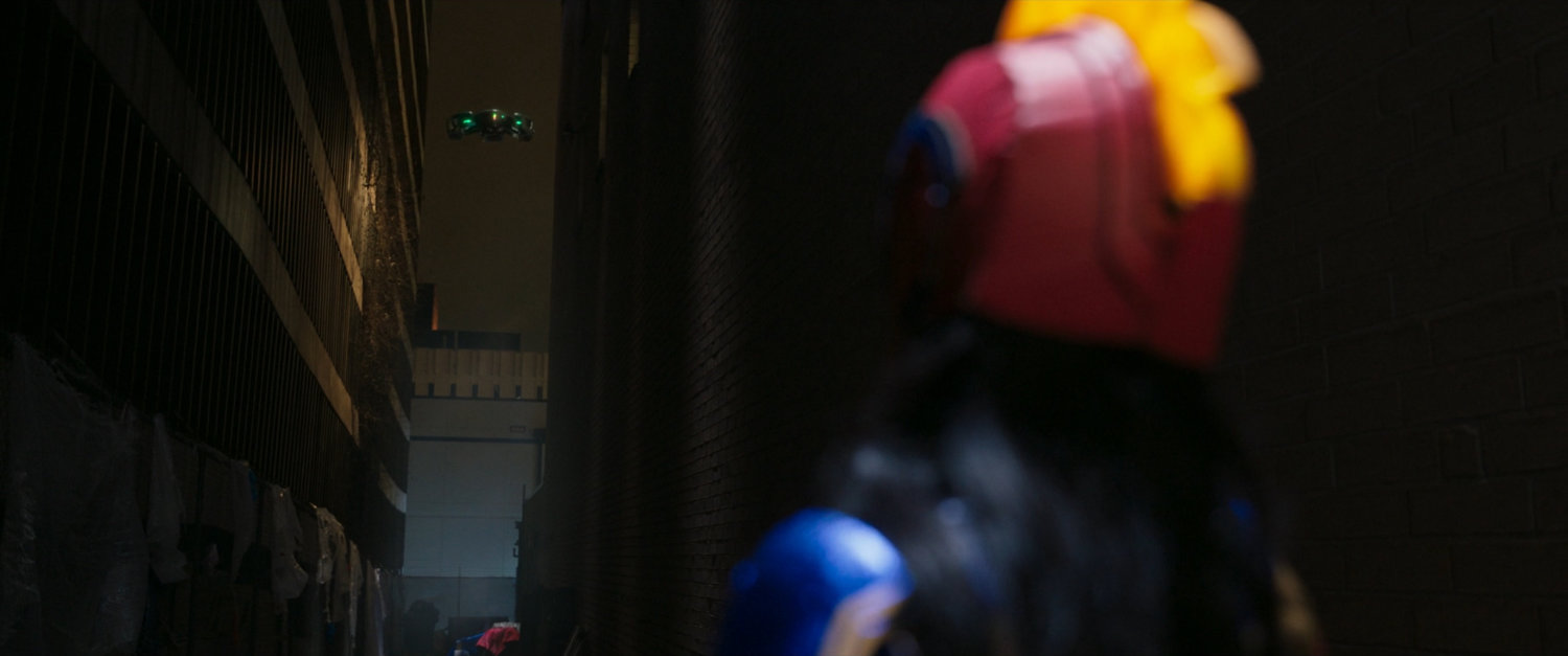 Kamala spots a DODC drone in a dark alley.