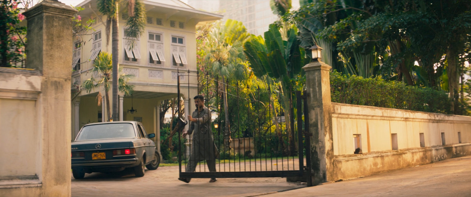 A guard closes a gate outside Sana's house.