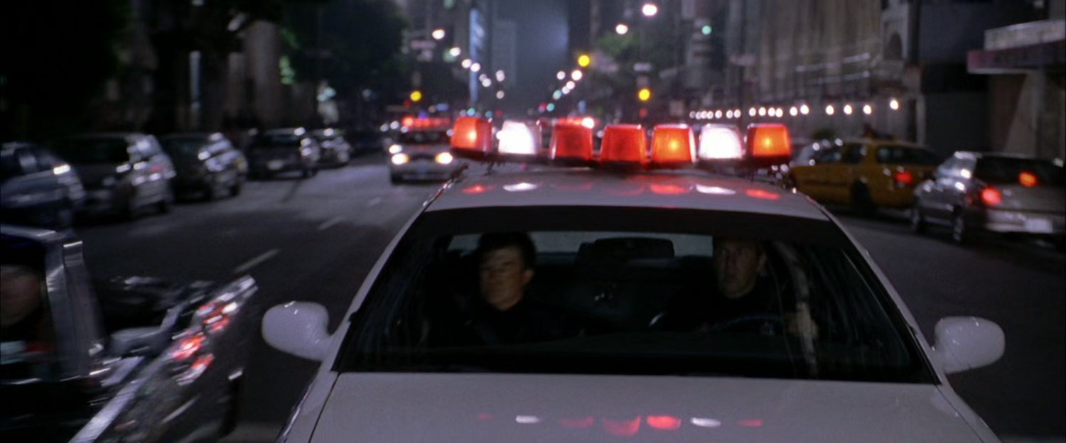 NYPD police car on street at night with lights.