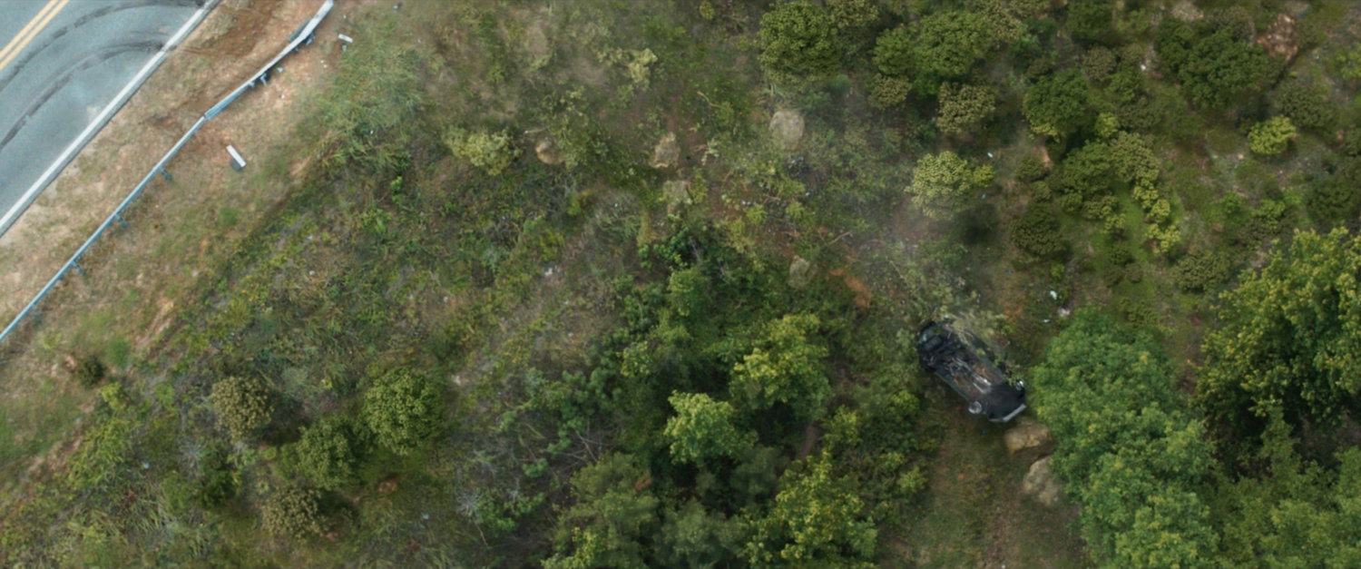 A Ford SUV tumbling down an embankment off a road.