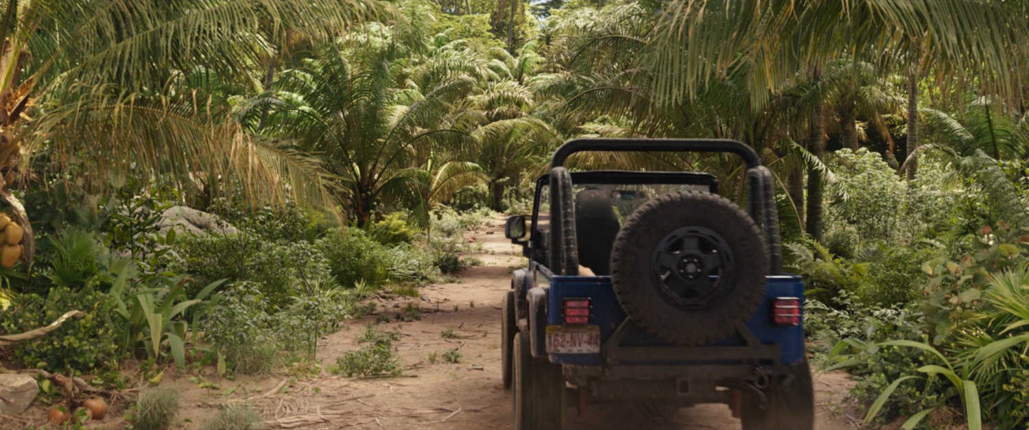 Jennifer Walters driving a Jeep away from camera in the jungle.