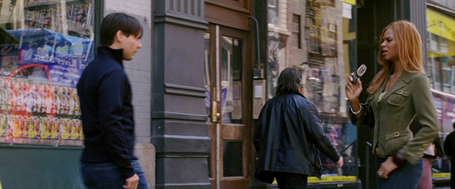 Peter Parker on sidewalk looking at a woman.