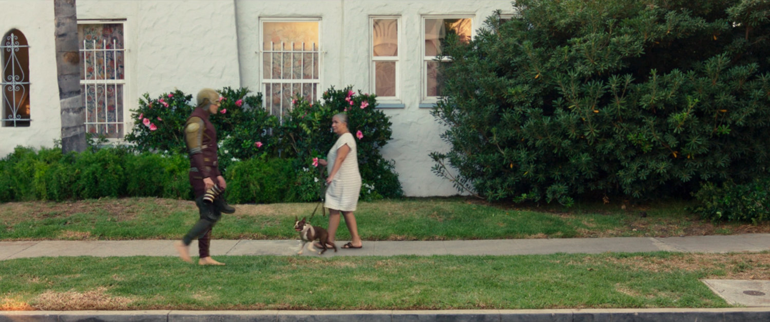 Daredevil walks past a woman walking a dog outside Jennifer Walters apartment.