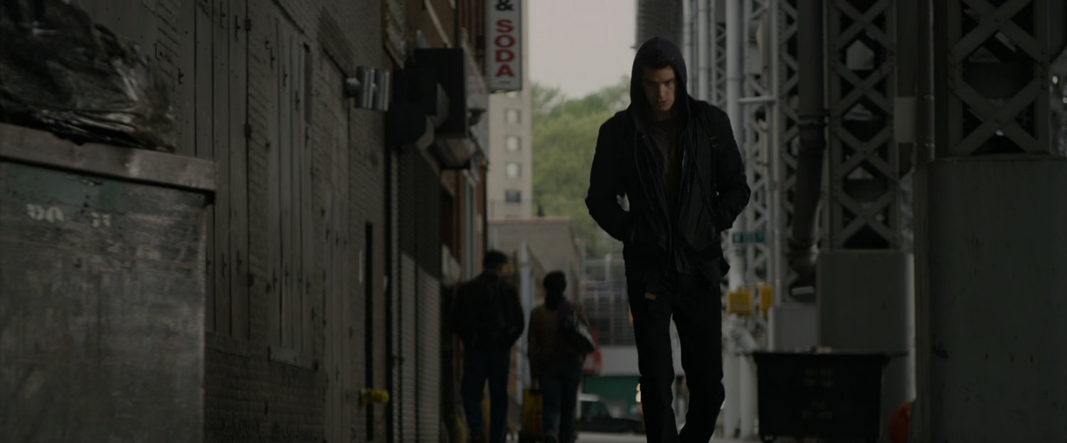 Peter Parker walks down sidewalk.