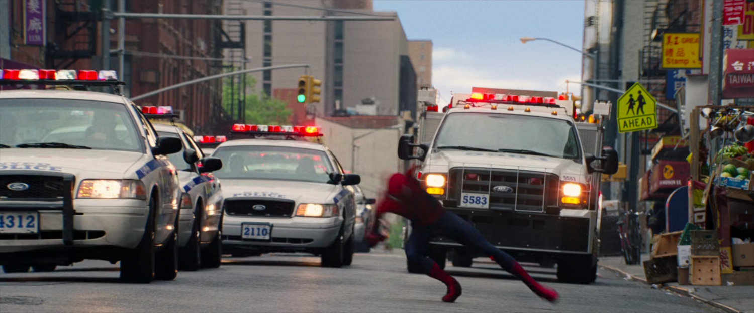 Spider-Man dodges police cars in the street.