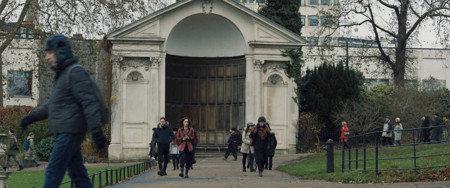G'iah and crowds in a Russian park, with a large alcove behind them.