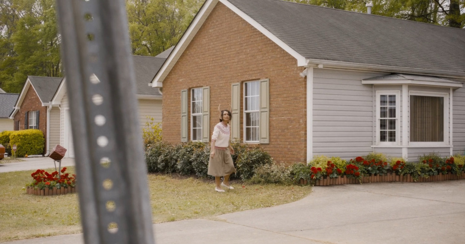 Female humanimal in front of suburban home.