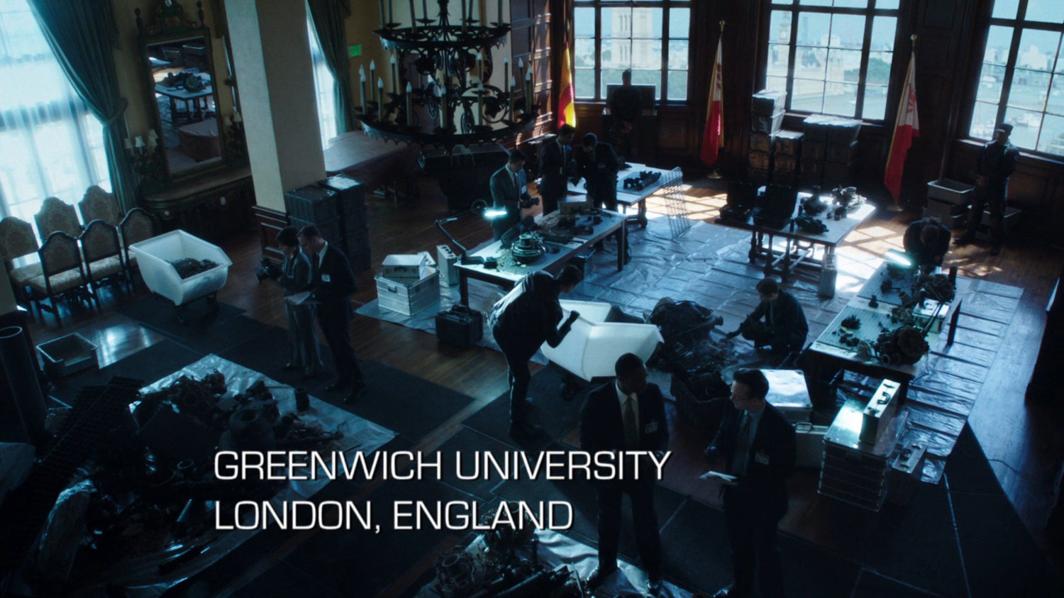 Interior of large office with collection bins strewn about. Text: Greenwich University, London, England.