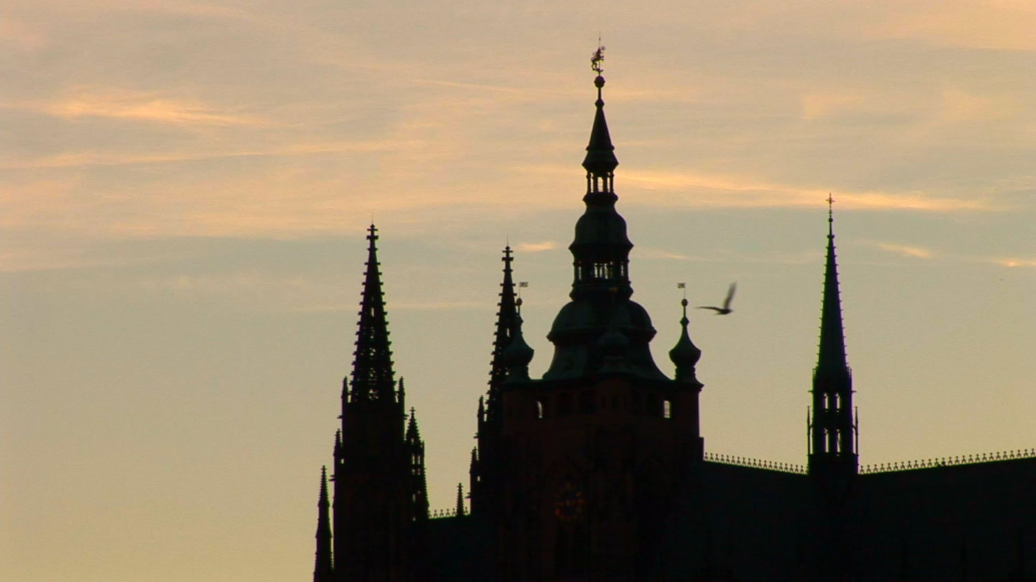 Silhouette of church spires against light skies.