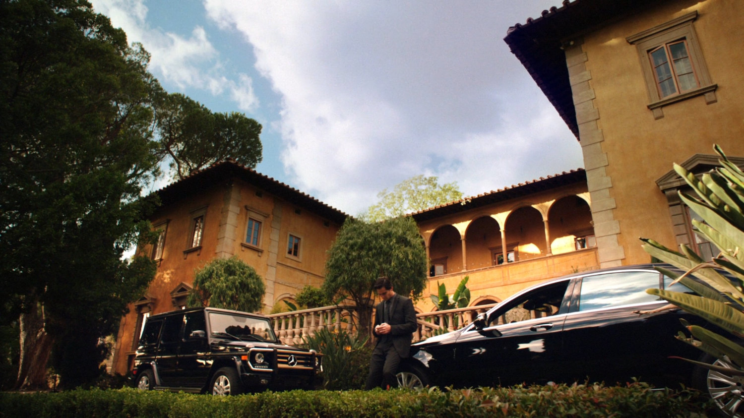 Exterior of Italian villa, with cars parked out front.