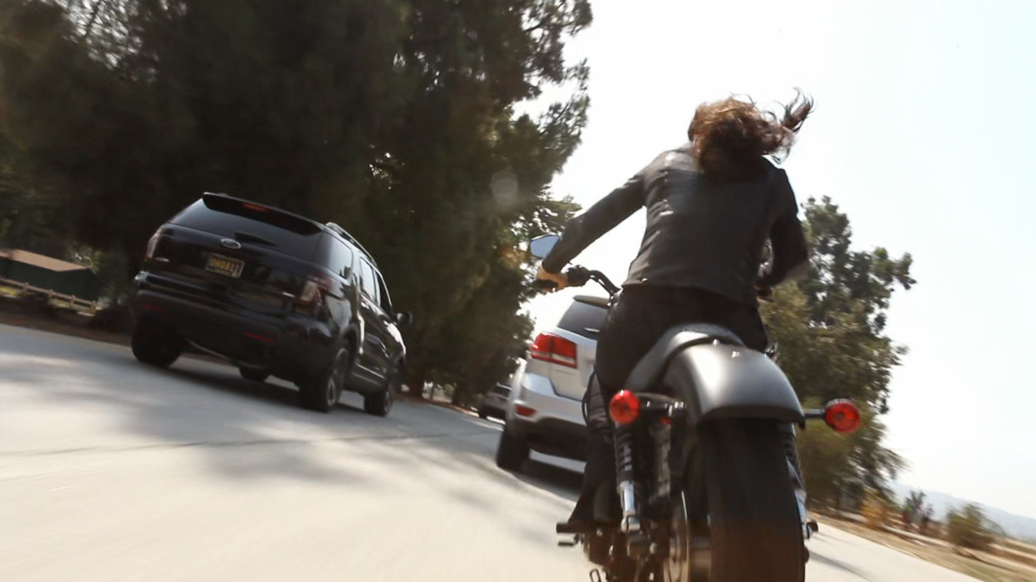 Agent May racing along a busy road on a motorcycle.