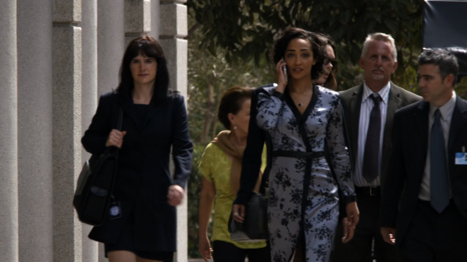Raina walking down a sidewalk with crowd behind her.