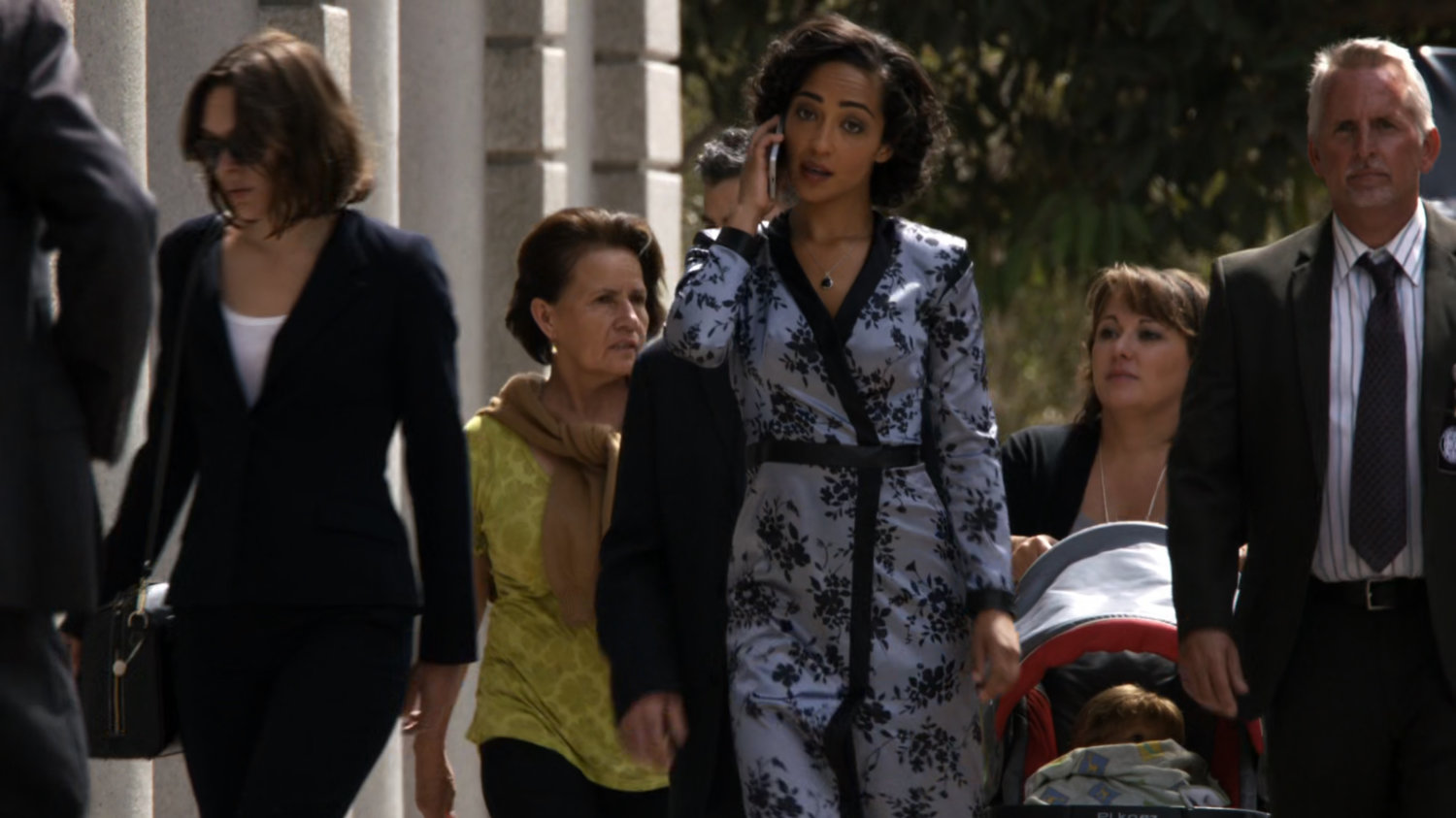 Raina walking down a sidewalk with crowd behind her.