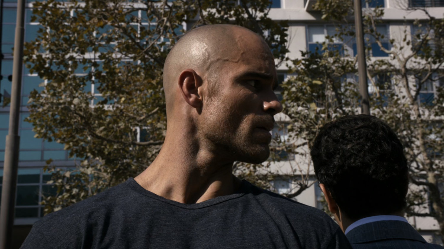Closeup of Creel talking with Bakshi in a city park.