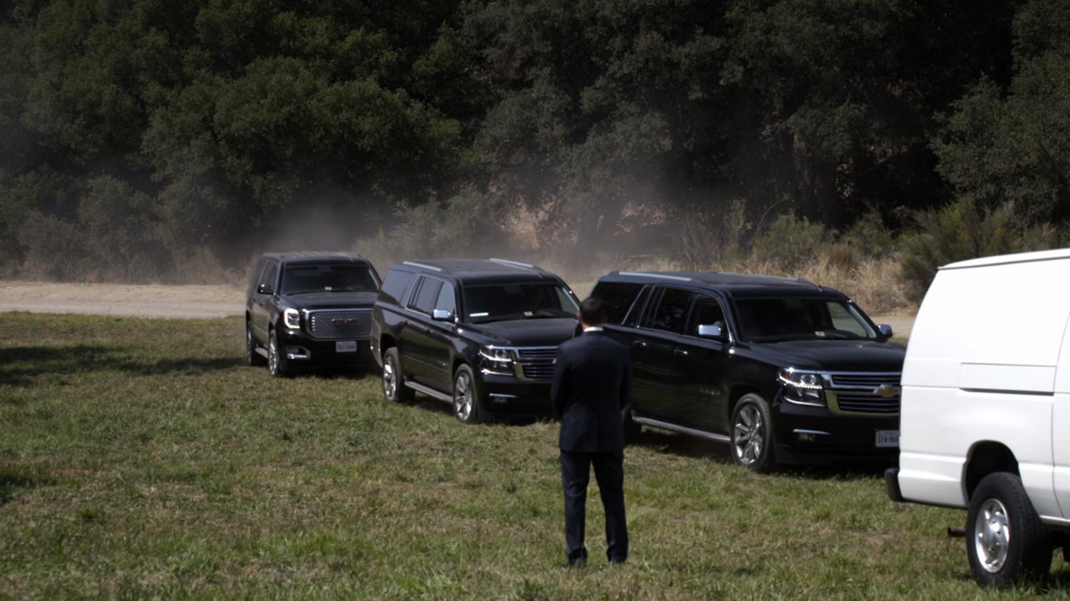Coulson in field with black SUVs approaching.