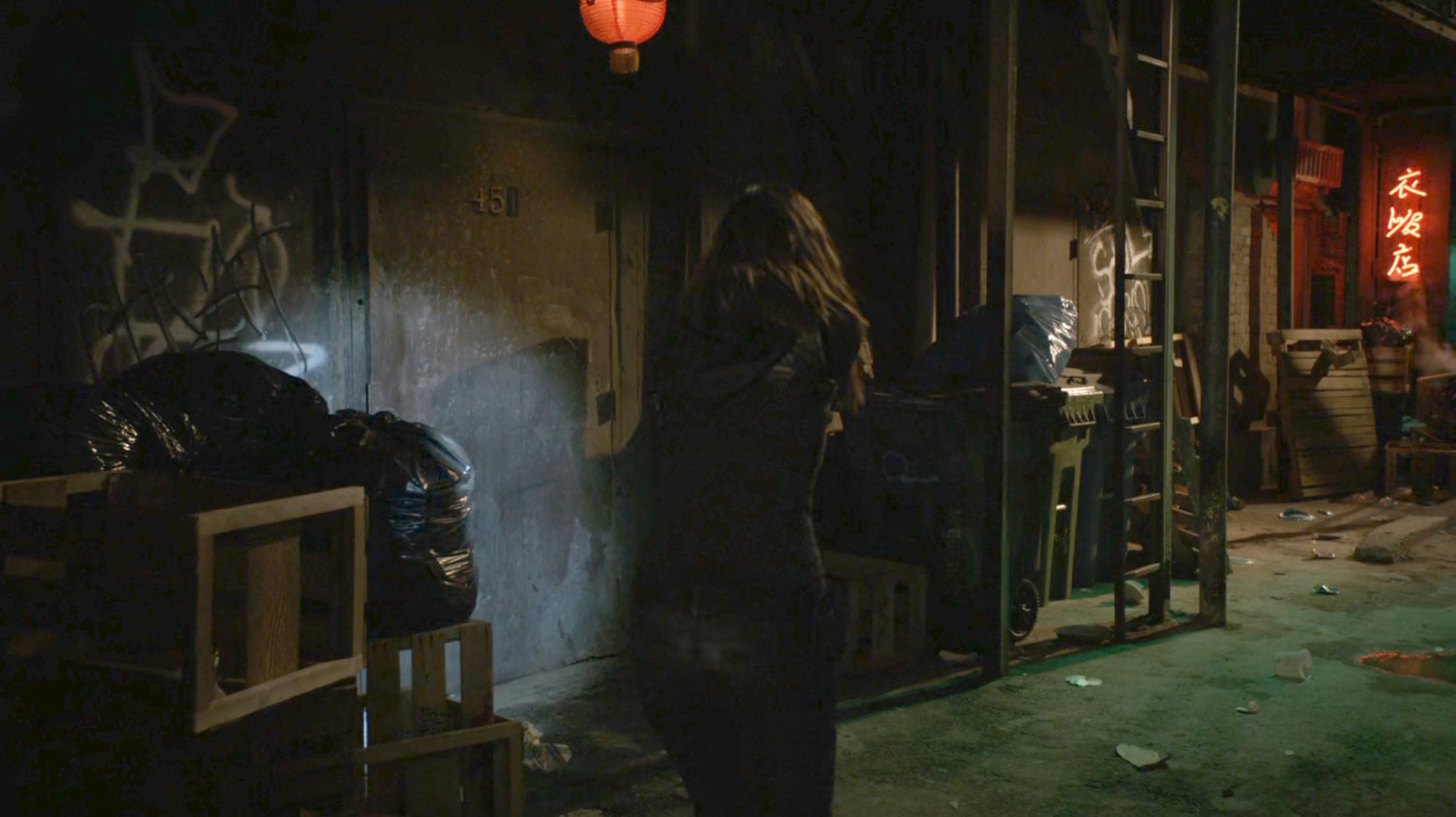 Skye in a dark, trashy alley with a neon sign of Chinese characters.