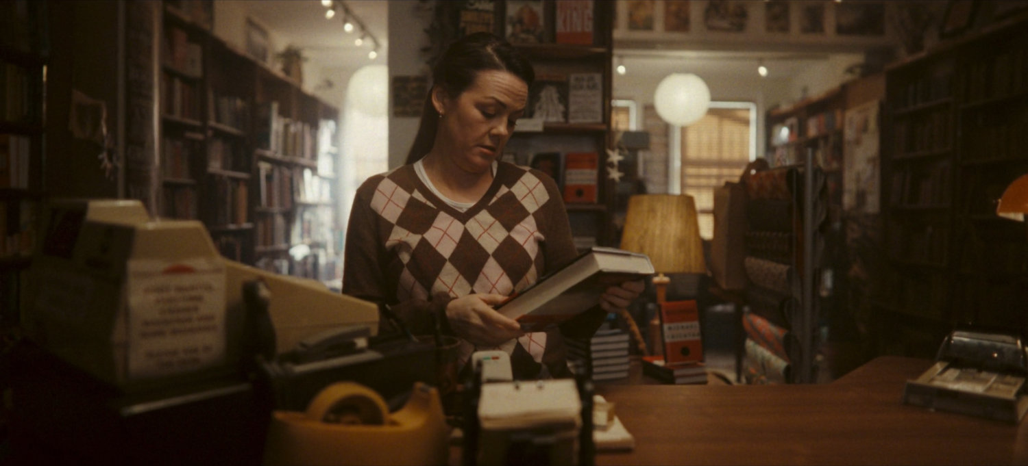 Salesperson at cash register in bookstore.