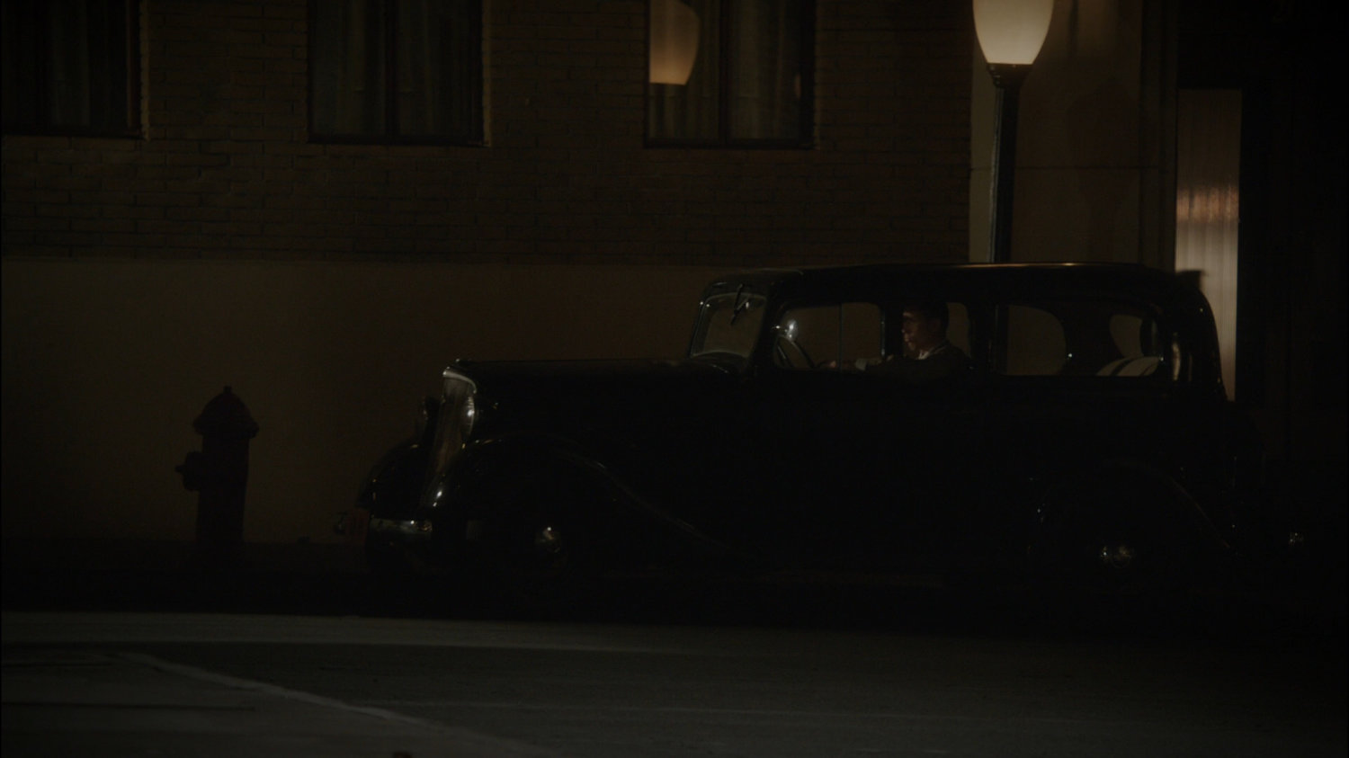 Car parked in front of dark New York city building.