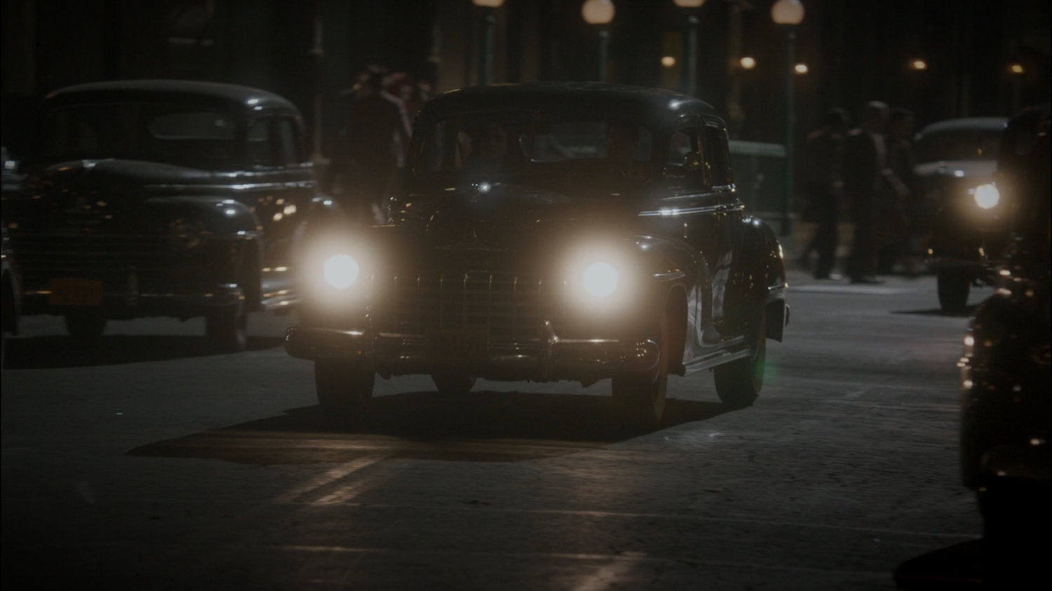 Car driving on New York city street at night.