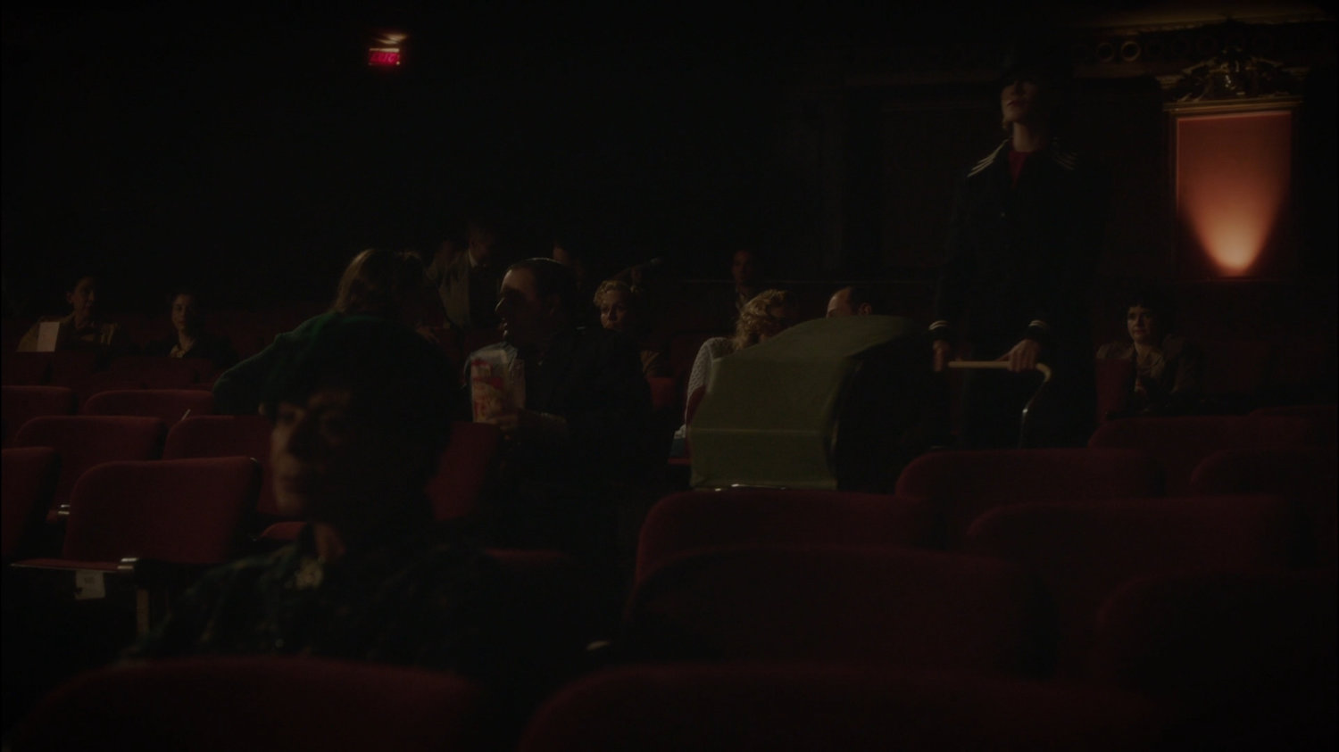 Dottie pushes baby stroller in movie theater.