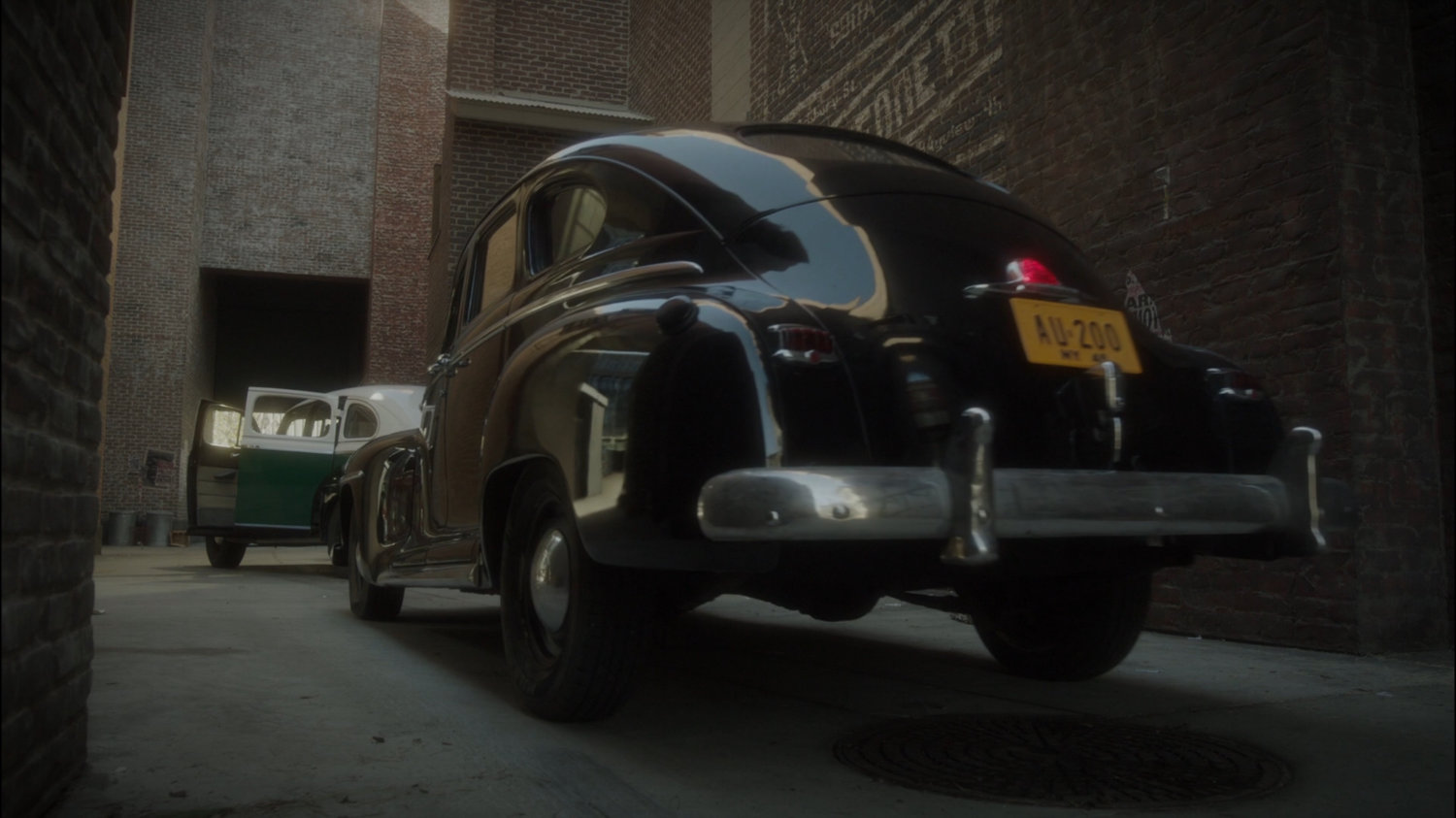 Car pulls in to New York alley behind empty police car.