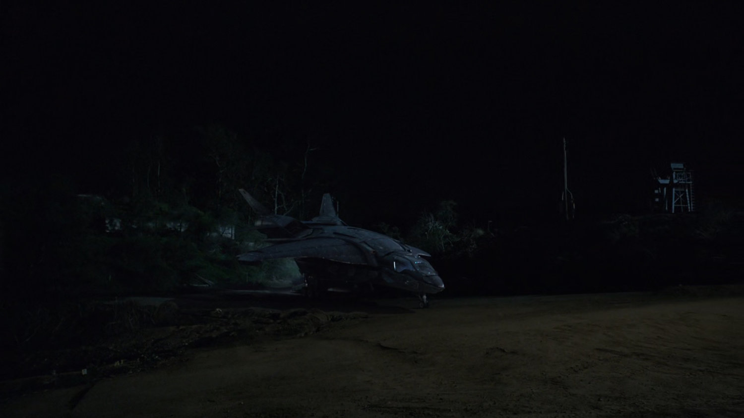 Quinjet parked next to oil field at nighttime.