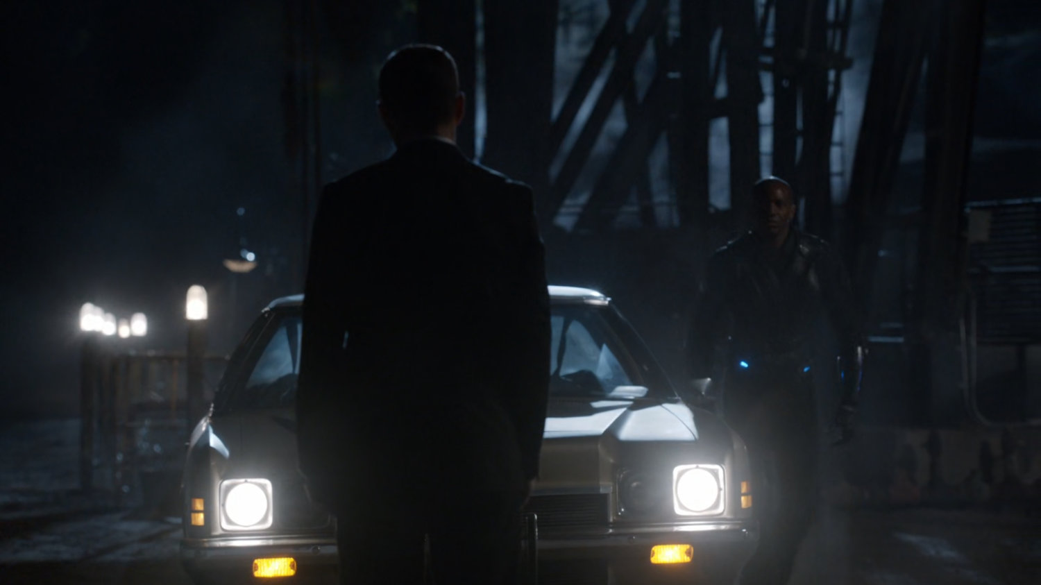 Coulson in oil field at night in front of car.