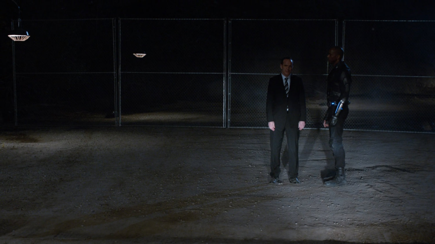Coulson and Deathlok illuminated by car headlights at night in oil field.