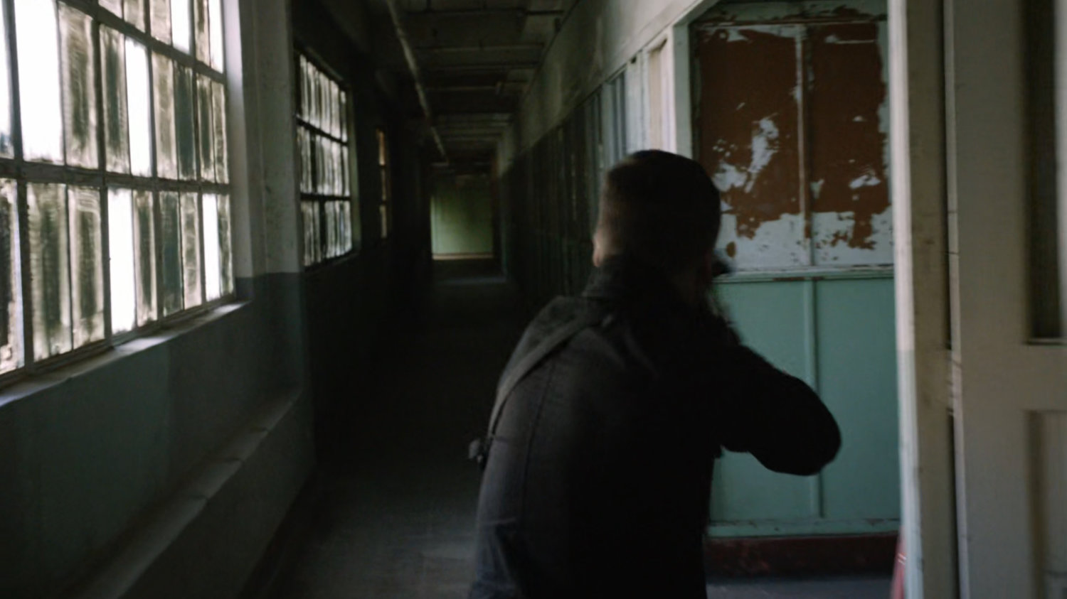 SHIELD Agent in a hallway of an abandoned Spanish warehouse.