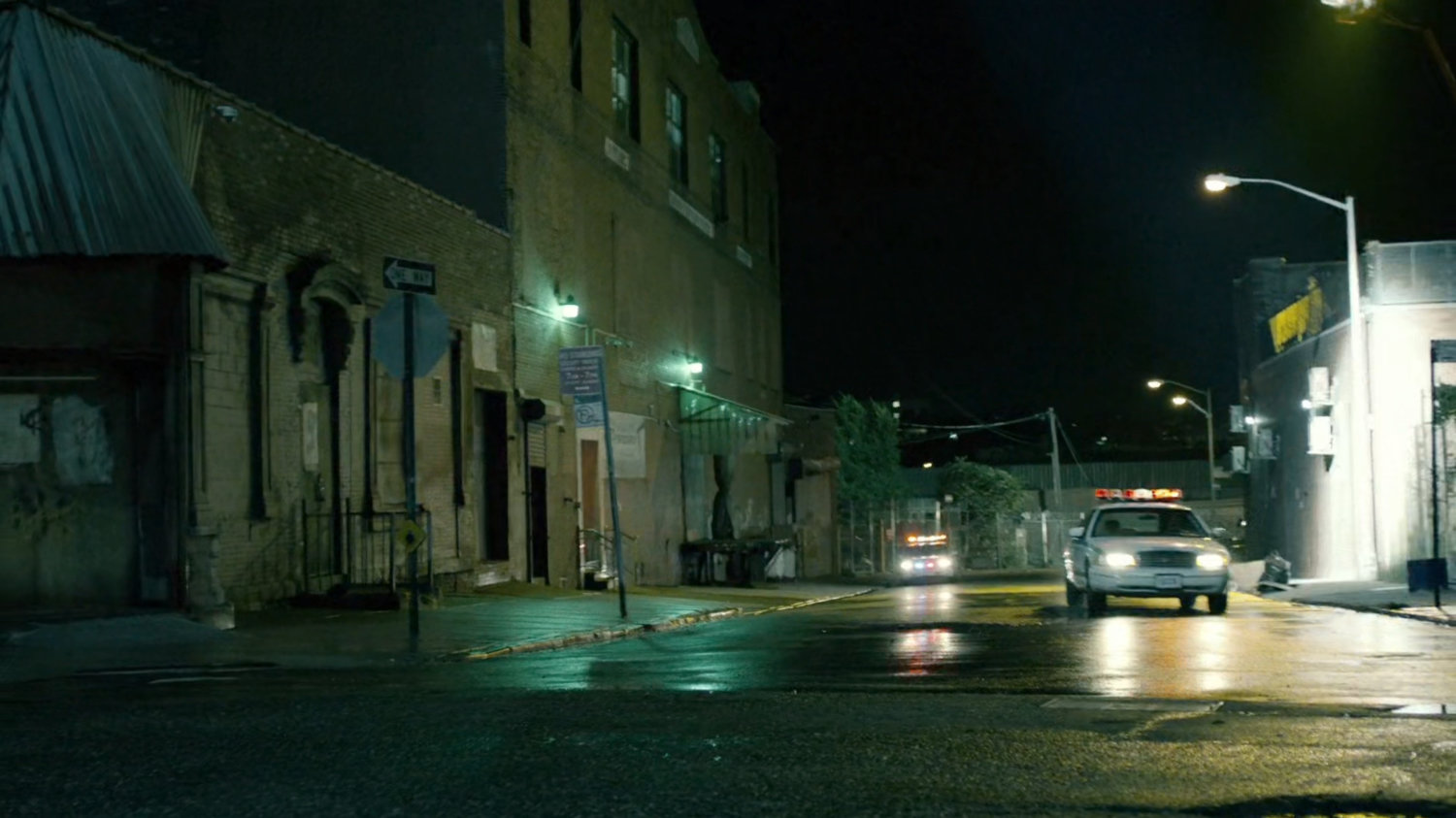 Police car on street outside of abandoned warehouse.