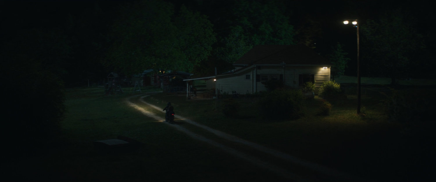 Motorcycle pulls up to Lopez house at night.