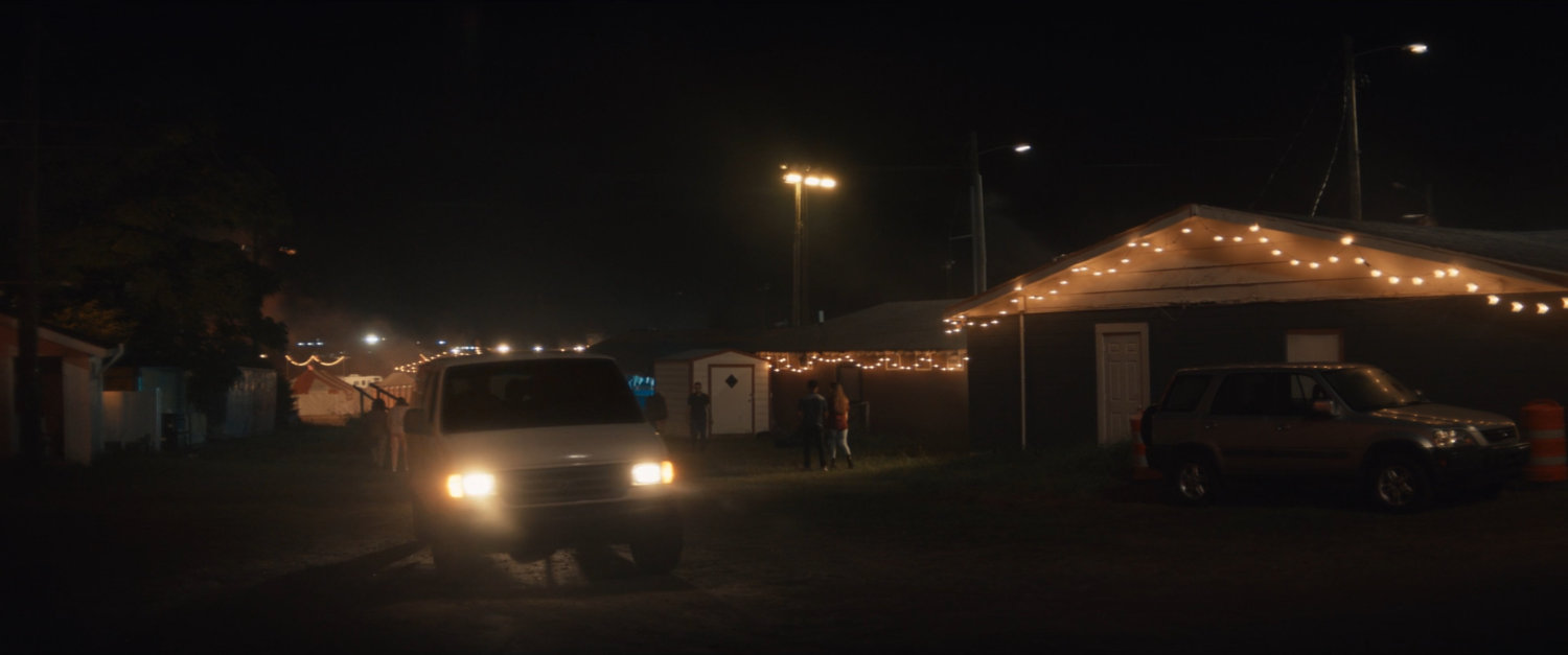 Vans pull through the Choctaw Nation PowWow at night.