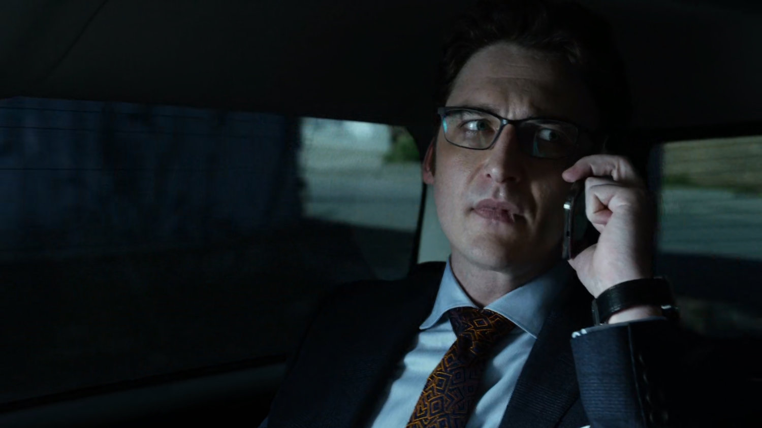 Wesley on phone in back seat of car.