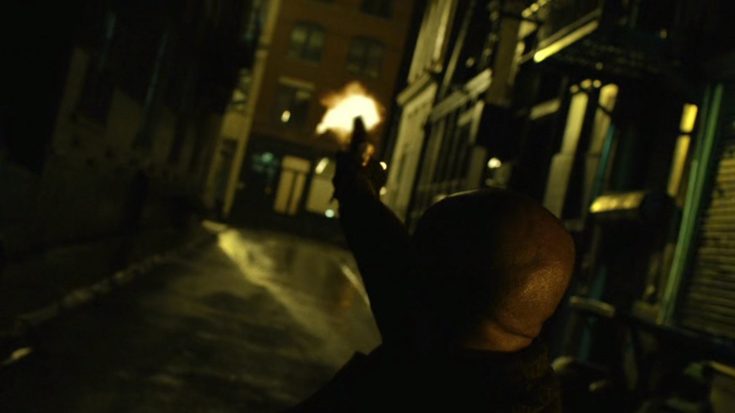Turk firing his gun in a dark alley.