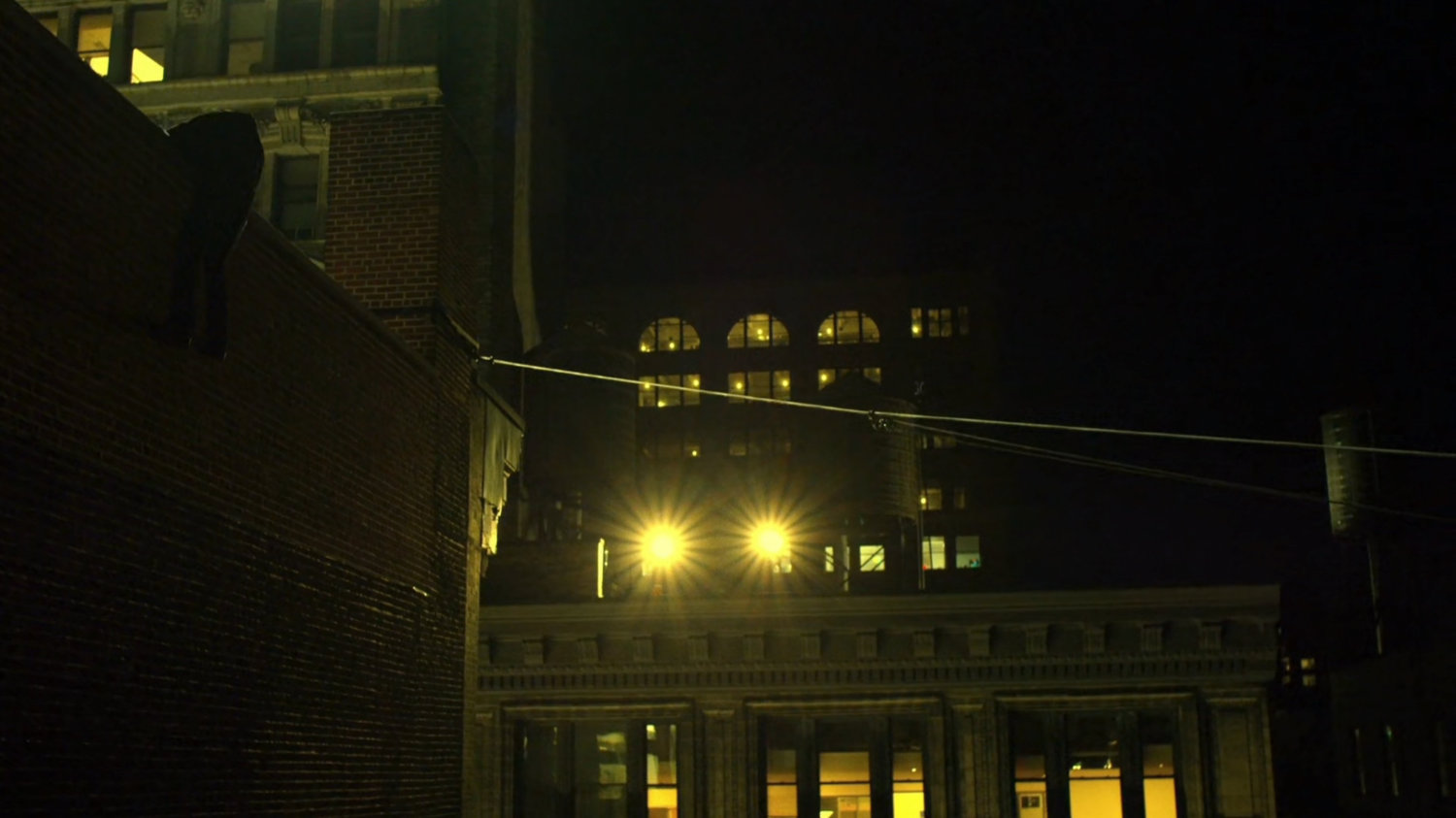 Turk climbing over a rooftop ledge.