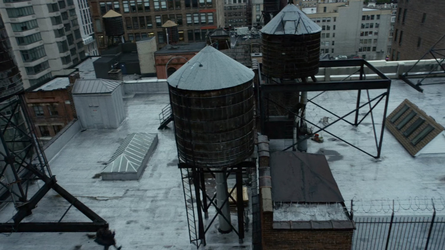 Matt runs across a New York rooftop, by a water towers.