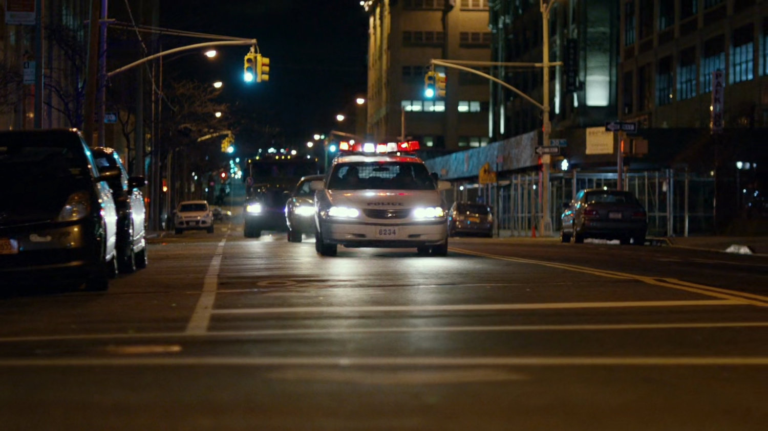Police cars drive along a city street.