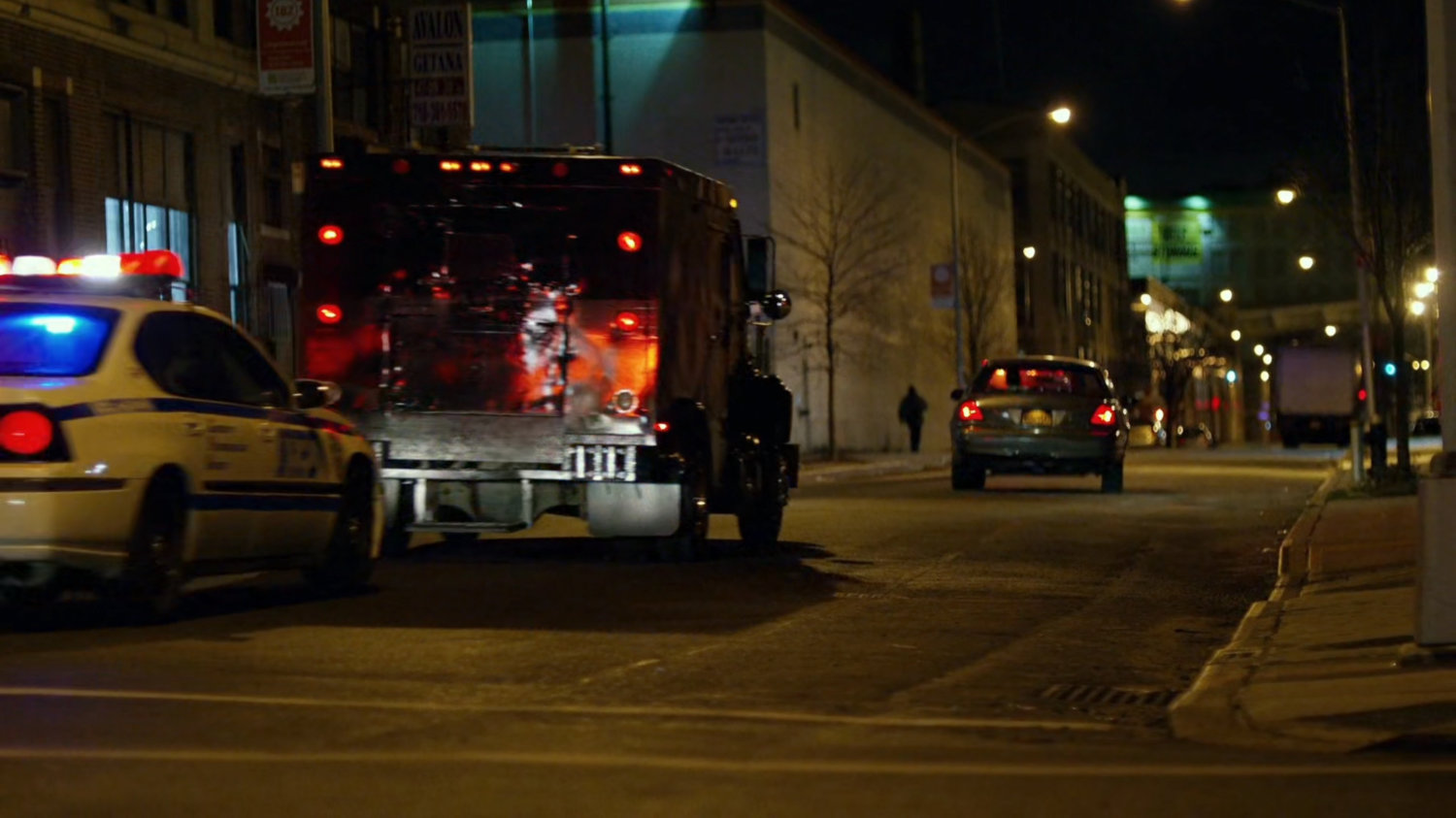Police cars drive along a city street.