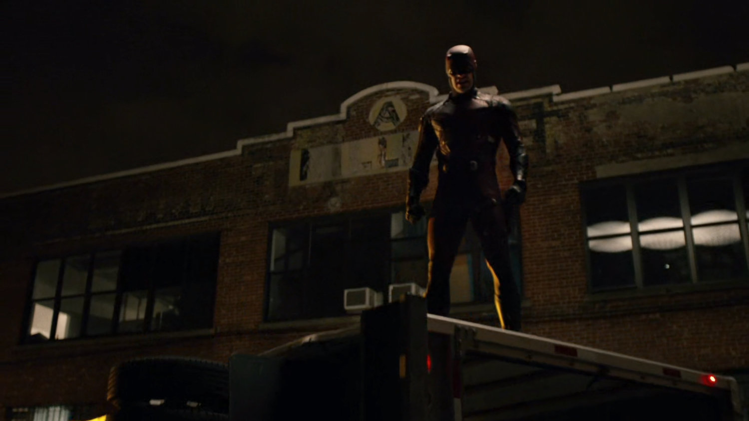 Daredevil standing on top of flipped truck.
