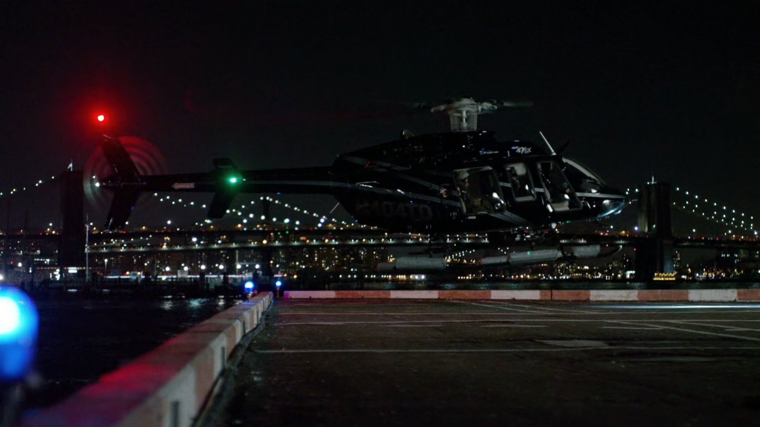 Helicopter departing heliport with bridges in background.