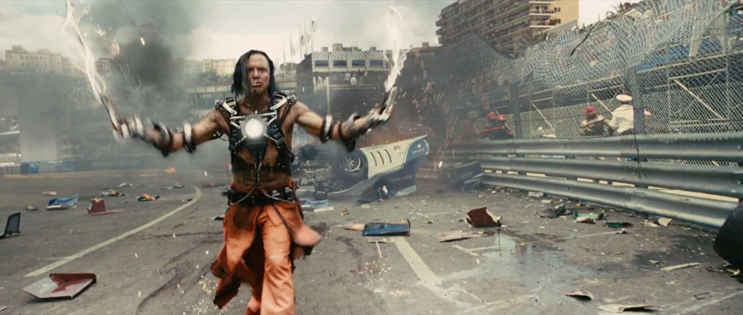 Whiplash standing on the race track with debris behind him.